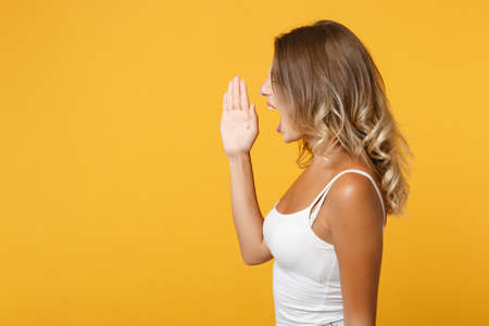 Side view of young woman in light casual clothes posing isolated on yellow orange wall background...