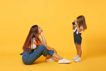 Woman in light clothes have fun with cute child baby girl 4-5 years old. Mommy little kid daughter isolated on yellow background studio portrait. Mothers Day love family parenthood childhood concept.の写真素材