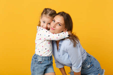 Woman in light clothes have fun with cute child baby girl 4-5 years old. Mommy little kid daughter isolated on yellow background studio portrait. Mothers Day love family parenthood childhood concept.の写真素材
