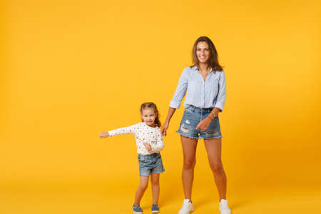 Woman in light clothes have fun with cute child baby girl 4-5 years old. Mommy little kid daughter isolated on yellow background studio portrait. Mothers Day love family parenthood childhood concept.の写真素材