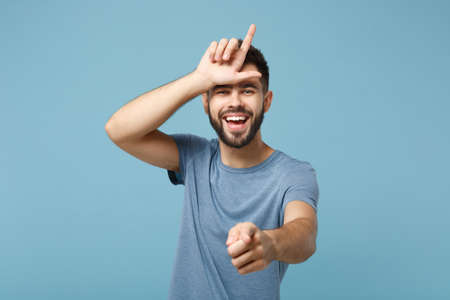 Young laughing man in casual clothes posing isolated on blue wall background, studio portrait....