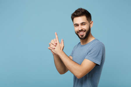 Young smiling handsome attractive man in casual clothes posing isolated on blue wall background,...