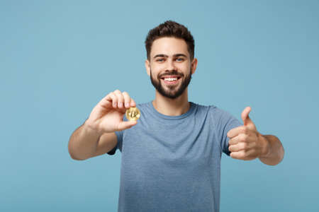Young smiling man in casual clothes posing isolated on blue wall background in studio. People...