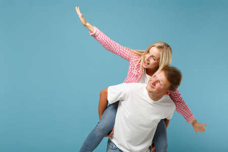 Young fun couple two friends guy girl in white pink empty blank design t-shirts posing isolated on...