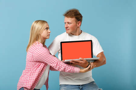 Young concerned couple two friend guy girl in white pink t-shirts posing isolated on pastel blue...