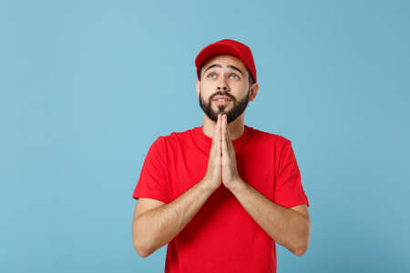Delivery man in red uniform workwear isolated on blue wall background, studio portrait. Professional...