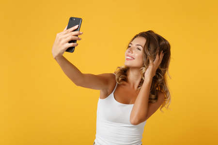 Smiling young woman girl in light casual clothes posing isolated on yellow orange background. People...