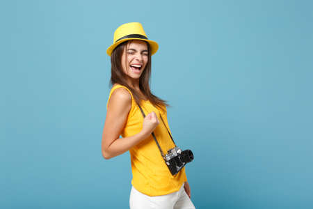 Traveler tourist woman in yellow summer casual clothes, hat with photo camera isolated on blue background. Female passenger traveling abroad to travel on weekends getaway. Air flight journey concept.の写真素材