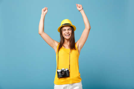 Traveler tourist woman in yellow summer casual clothes, hat with photo camera isolated on blue background. Female passenger traveling abroad to travel on weekends getaway. Air flight journey concept.の写真素材