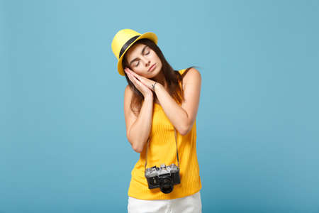 Traveler tourist woman in yellow summer casual clothes, hat with photo camera isolated on blue background. Female passenger traveling abroad to travel on weekends getaway. Air flight journey concept.の写真素材