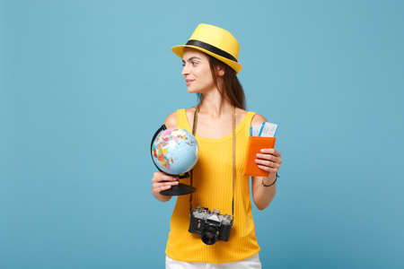 Traveler tourist woman in yellow summer casual clothes, hat hold globe tickets isolated on blue...