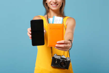 Cropped traveler tourist woman in yellow clothes hold tickets cellphone camera isolated on blue background. Female passenger traveling abroad travel on weekends getaway. Air flight journey concept.の写真素材