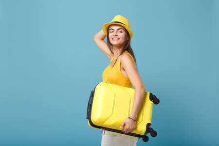 Traveler tourist woman in yellow casual clothes, hat with suitcase photo camera isolated on blue background. Female passenger traveling abroad to travel on weekends getaway. Air flight journey conceptの写真素材