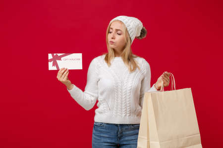 Pretty young woman in sweater, hat isolated on red background. Healthy fashion lifestyle, cold...