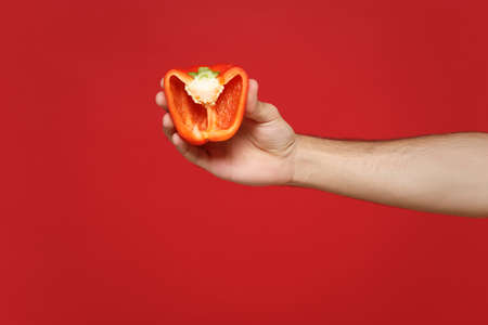 Close up cropped photo of male holding in hands half of fresh vegetable bell pepper isolated on bright wall background in studio. Copy space advertising mock up. Cooking healthy food concept.の写真素材