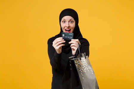 Arabian muslim woman in black hijab hold package bag, purchases shopping bank card isolated on...