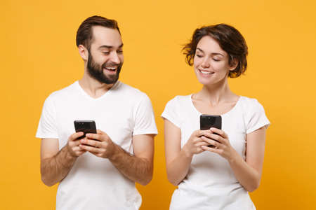 Funny young couple friends bearded guy girl in white blank empty t-shirts isolated on yellow orange background.の写真素材