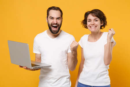 Joyful couple friends bearded guy girl in white blank empty t-shirts isolated on yellow orange background.の写真素材