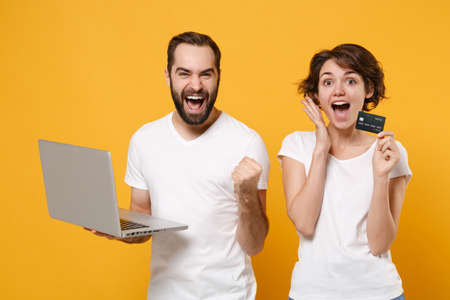 Excited couple friends bearded guy girl in white t-shirts isolated on yellow orange background.の写真素材