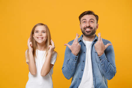 Bearded man have fun with child baby girl. Father, little kid daughter isolated on yellow background. Love family day parenthood childhood. Wait for special moment keeping fingers crossed making wish.の写真素材