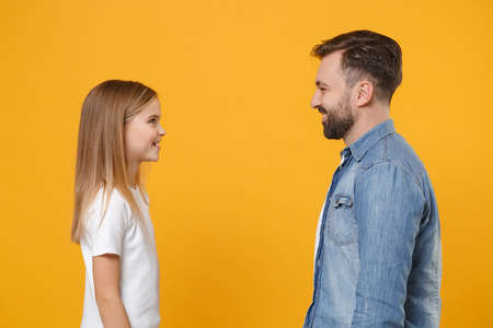 Side view of bearded man in casual clothes have fun with child baby girl. Father little kid daughter isolated on yellow background. Love family day parenthood childhood concept. Looking at each other.の写真素材