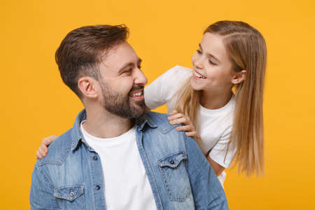 Funny bearded man in casual clothes have fun with cute child baby girl. Father little kid daughter isolated on yellow background. Love family day parenthood childhood concept. Looking at each other.の写真素材