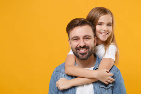 Smiling bearded man in casual clothes have fun with cute child baby girl. Father little kid daughter isolated on yellow background in studio. Love family day parenthood childhood concept. Hugging.の写真素材