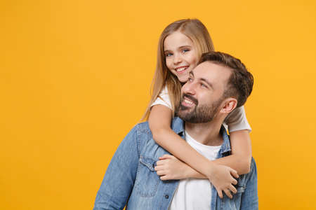 Cheerful bearded man in casual clothes have fun with cute child baby girl. Father little kid daughter isolated on yellow background in studio. Love family day parenthood childhood concept. Hugging.の写真素材