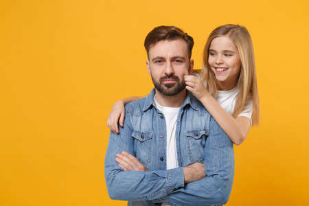 Bearded man in casual clothes have fun with cute child baby girl. Father little kid daughter isolated on yellow wall background. Love family day parenthood childhood concept. Hugging, touching cheek.の写真素材