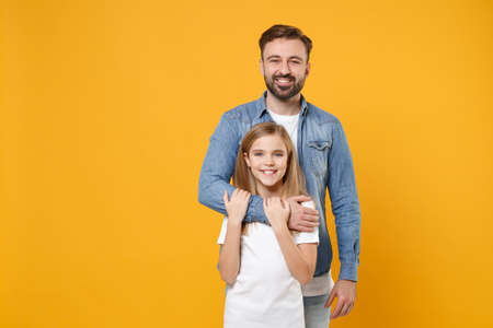 Smiling bearded man in casual clothes have fun with cute child baby girl. Father little kid daughter isolated on yellow background in studio. Love family day parenthood childhood concept. Hugging.の写真素材