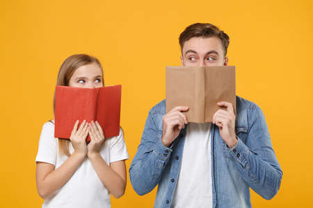 Pretty bearded man in casual clothes have fun with child baby girl. Father little kid daughter isolated on yellow background. Love family day parenthood childhood concept. Covering face with book.の写真素材