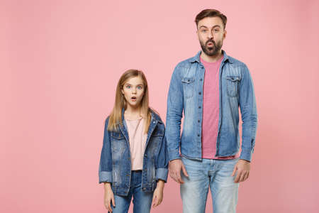Shocked bearded man in casual clothes with child baby girl. Father little kid daughter isolated on pastel pink background studio portrait.の写真素材