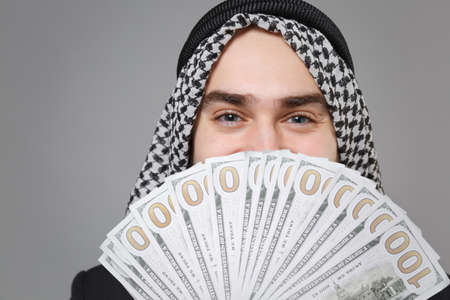 Close up of young arabian muslim businessman in keffiyeh kafiya ring igal agal isolated on gray...