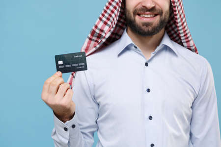 Cropped image of young bearded arabian muslim man in keffiyeh kafiya ring igal agal casual clothes posing isolated on pastel blue background.の写真素材