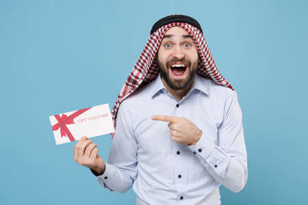 Excited bearded arabian muslim man in keffiyeh kafiya ring igal agal casual clothes isolated on pastel blue background.の写真素材