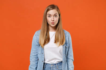 Pretty young woman girl in casual denim clothes posing isolated on bright orange wall background studio portrait.の写真素材