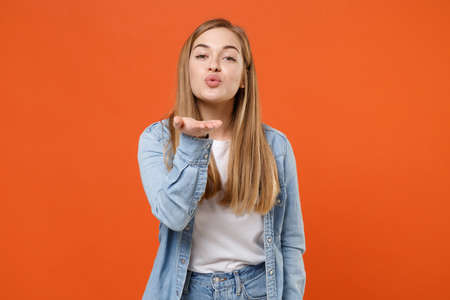 Cute young woman girl in casual denim clothes posing isolated on bright orange wall background studio portrait.の写真素材