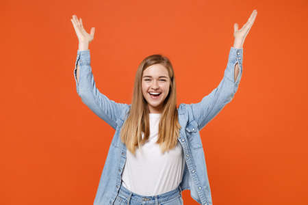 Cheerful joyful young woman girl in casual denim clothes posing isolated on orange background studio portrait.の写真素材