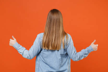 Back rear view of young woman girl in casual denim clothes posing isolated on orange wall background...