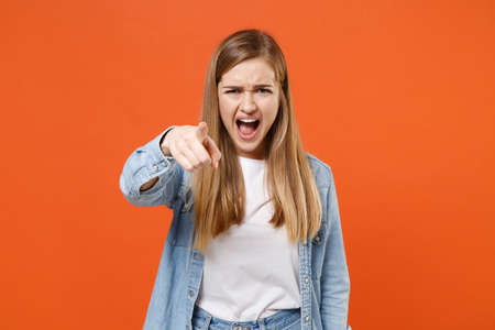 Angry young woman girl in casual denim clothes posing isolated on orange background studio portrait.の写真素材