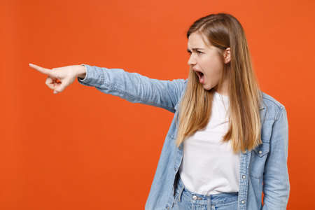 Irritated young woman girl in casual denim clothes posing isolated on orange background studio portrait.の写真素材