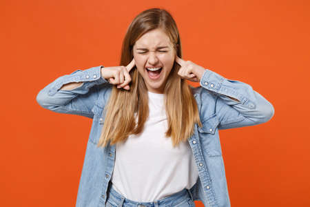 Crazy young woman girl in casual denim clothes posing isolated on orange background in studio.の写真素材