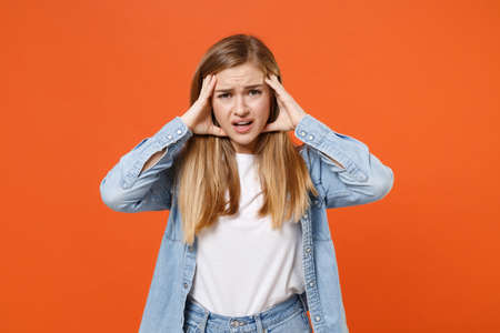 Preoccupied exhausted young woman girl in casual denim clothes posing isolated on orange background studio portrait.の写真素材