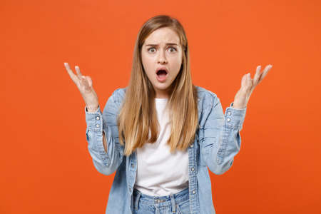 Shocked young woman girl in casual denim clothes posing isolated on orange wall background studio portrait.の写真素材