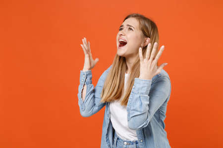 Worried young woman girl in casual denim clothes posing isolated on orange wall background studio portrait.の写真素材