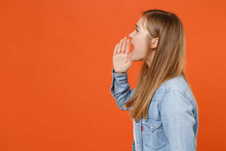 Side view of young woman girl in casual denim clothes posing isolated on orange background studio portrait.の写真素材