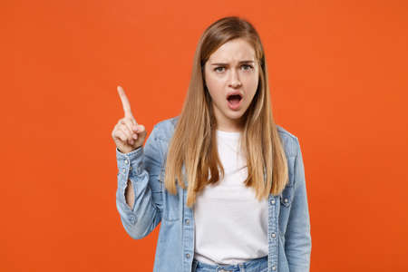 Shocked irritated young woman girl in casual denim clothes posing isolated on orange background studio portrait.の写真素材