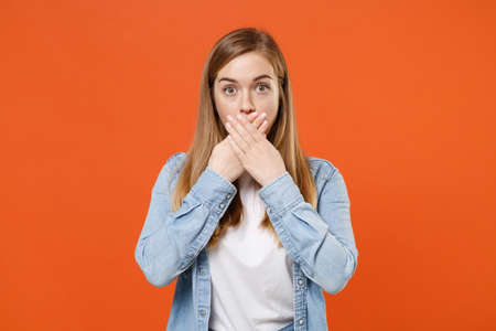 Shocked young woman girl in casual denim clothes posing isolated on orange wall background studio portrait.の写真素材