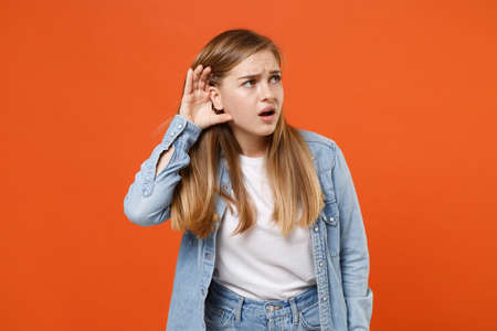 Curious young woman girl in casual denim clothes posing isolated on orange wall background studio portrait.の写真素材