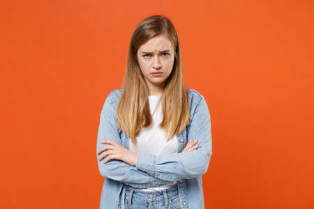Offended displeased young woman girl in casual denim clothes posing isolated on orange background studio portrait.の写真素材